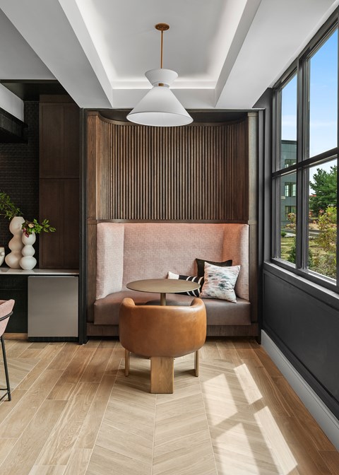 A modern living room with a brown sofa and a round wooden table.