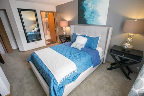 A bedroom with a large bed and a painting on the wall.