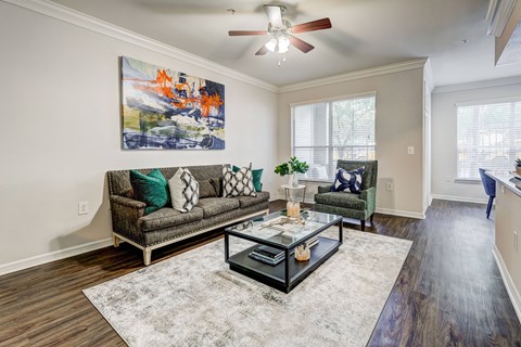 A living room with a grey couch, a coffee table, and a painting on the wall.