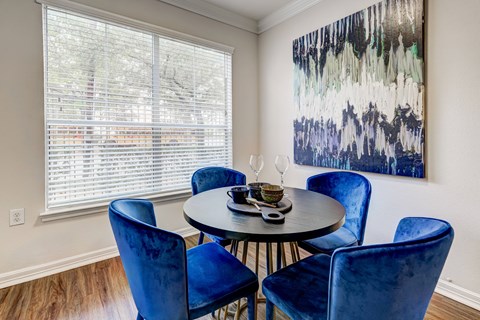 A dining room with a round table and blue chairs.