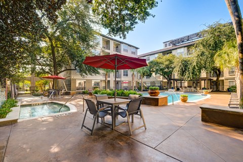 A patio with a table and chairs and a pool.