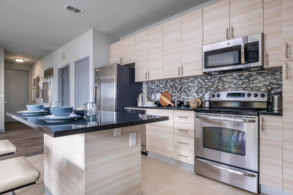 Reveal Heathrow apartments kitchen with custom cabinetry and quartz countertops