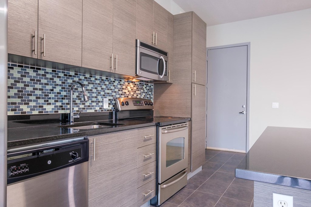 Reveal Heathrow apartments kitchen with custom cabinetry and tile backsplash
