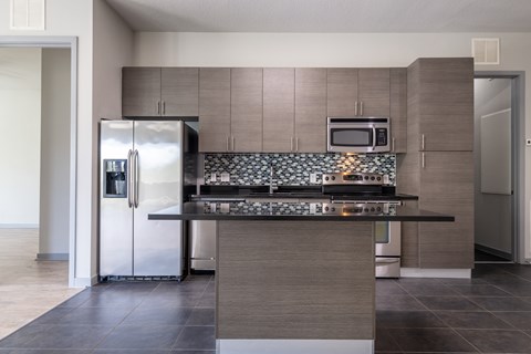 A modern kitchen with a stainless steel refrigerator and microwave above the counter.