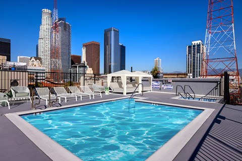 A pool on a rooftop with a city skyline in the background.