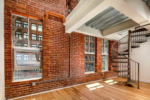 A room with a brick wall and a spiral staircase.