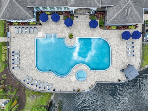 An aerial view of a swimming pool surrounded by blue umbrellas and lounge chairs.