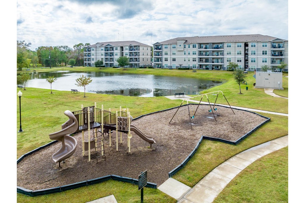 an aerial view of a playground and a pond at Retreat at Magnolia apartments
