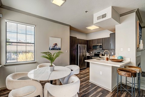 A kitchen with a table and chairs in front of a window.