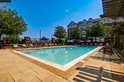 A large outdoor swimming pool surrounded by lounge chairs and trees.