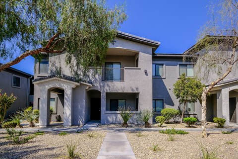 A modern house with a grey exterior and a gravel driveway.