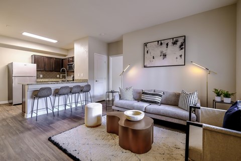 A modern living room with a grey couch, a white rug, and a painting on the wall.