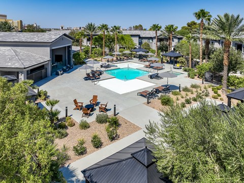 A pool surrounded by palm trees and patio furniture.