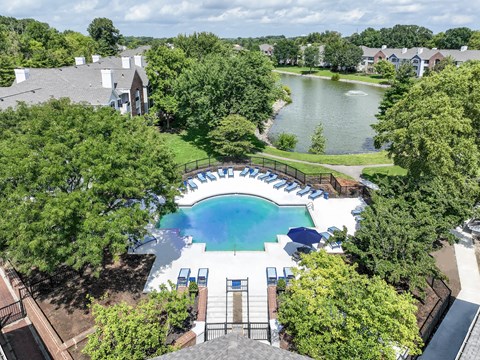 A large swimming pool surrounded by trees and a lake in the background.