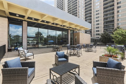 A patio with chairs and tables is surrounded by buildings.