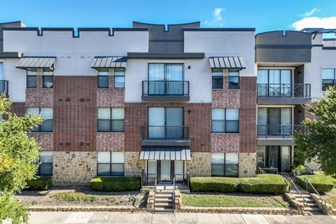 A multi-story apartment building with brick and stone exteriors and balconies.