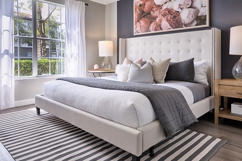 A bedroom with a large bed and a painting on the wall.