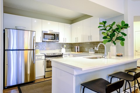 A modern kitchen with a stainless steel refrigerator and white countertops.