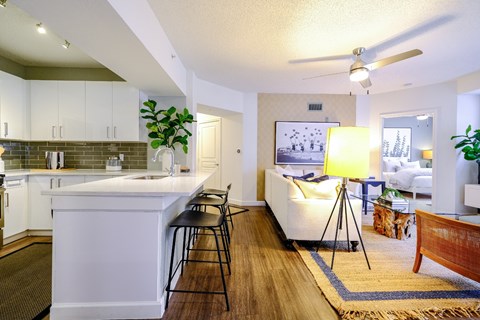 A modern kitchen with white cabinets and a white island with a bar stool.