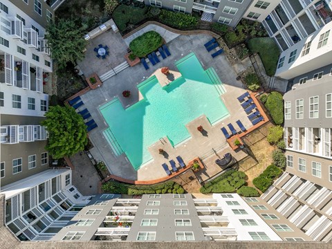 An aerial view of a pool surrounded by buildings and trees.
