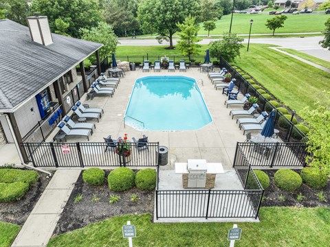 A pool surrounded by lounge chairs and a small building.