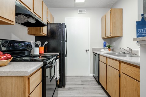 A kitchen with wooden cabinets and a black refrigerator.