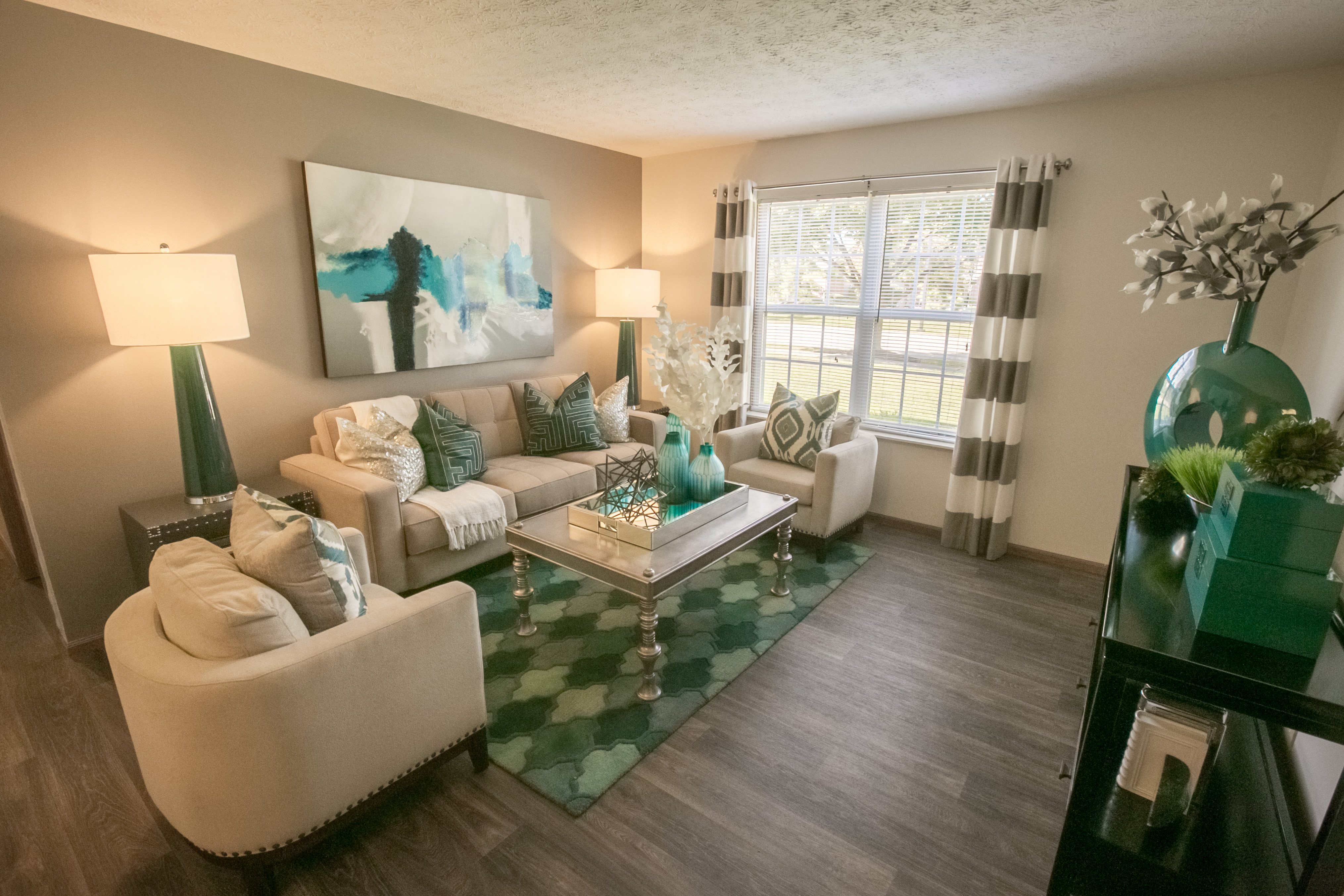 A living room with a white couch and a green and white rug.
