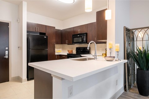 a kitchen with a white counter top and a black refrigerator