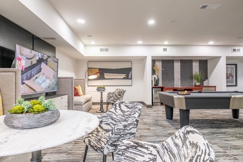 A modern living room with a pool table and a television.
