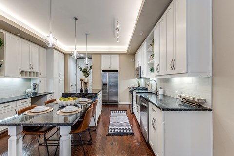 A modern kitchen with white cabinets and black countertops.