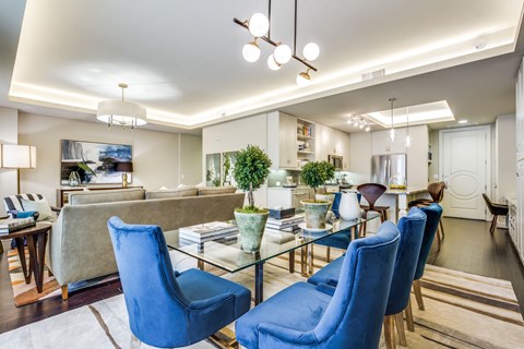 A modern living room with blue chairs and a glass table.