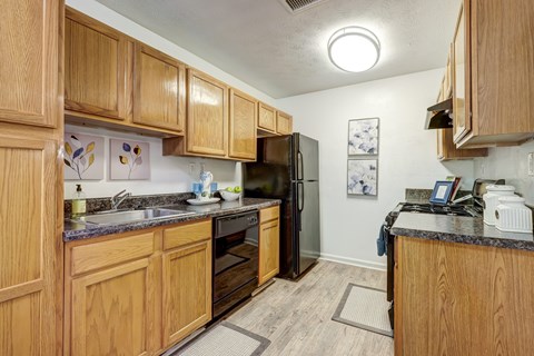 A kitchen with wooden cabinets and a black refrigerator.