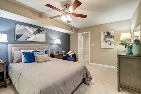 A bedroom with a large bed and a ceiling fan.