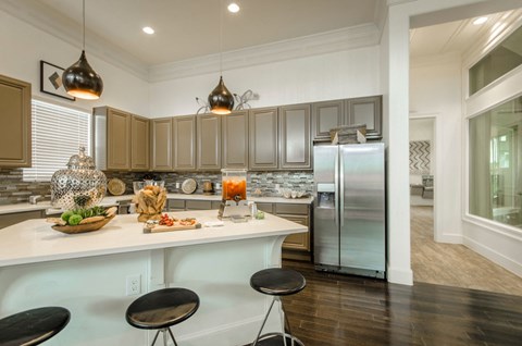 a kitchen with a large island and a stainless steel refrigerator