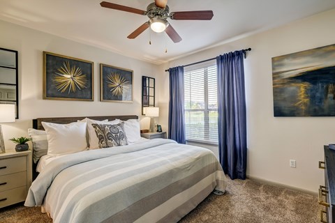 A bedroom with a large bed and a ceiling fan.