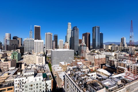 A cityscape with a mix of modern and older buildings, with a clear blue sky above.
