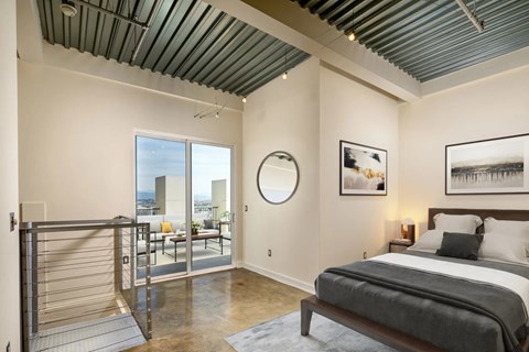 A bedroom with a bed, a round mirror, and a painting on the wall.