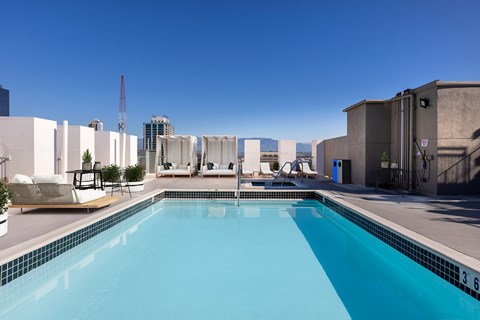 A swimming pool with a blue tiled edge and a white chair with a black cushion on the side.
