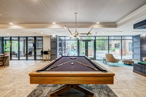 A pool table is in the middle of a room with a wood floor and a ceiling fan.