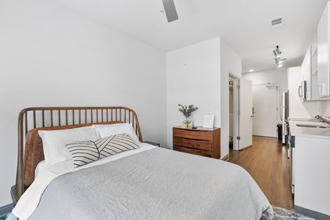 A bedroom with a bed, nightstand, and a plant on the nightstand.