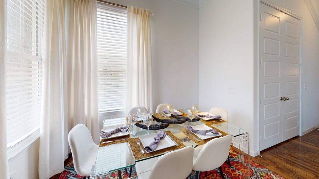 a dining room with a glass table and white chairs