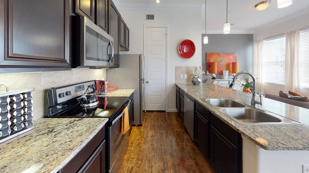 a kitchen with granite countertops and dark wood cabinets