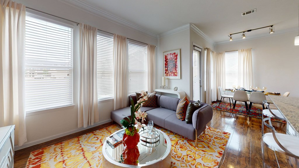 a living area with a couch coffee table and a dining room table in the background