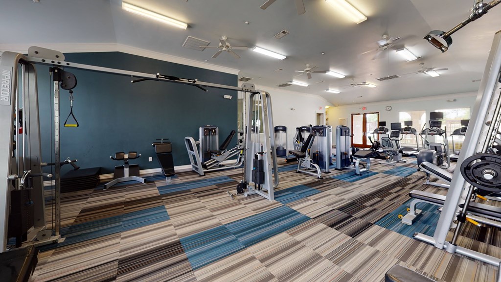 a large fitness room with cardio machines and weights