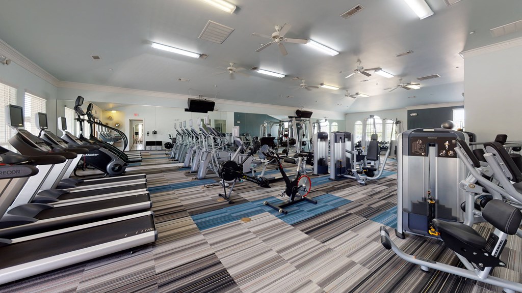 a large fitness room with cardio machines and weights