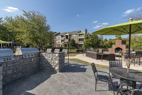 A patio with a stone fireplace and chairs.