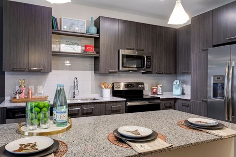 A modern kitchen with dark wood cabinets and a granite countertop.