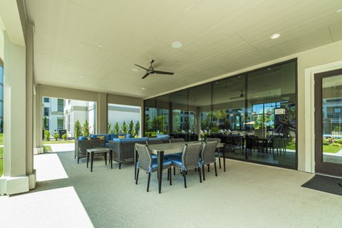 A spacious room with tables and chairs and a ceiling fan.