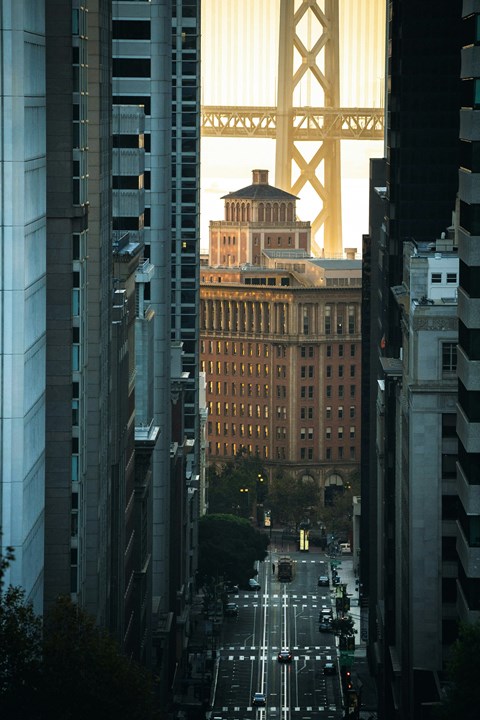 A view of a city street with the Golden Gate Bridge in the background.