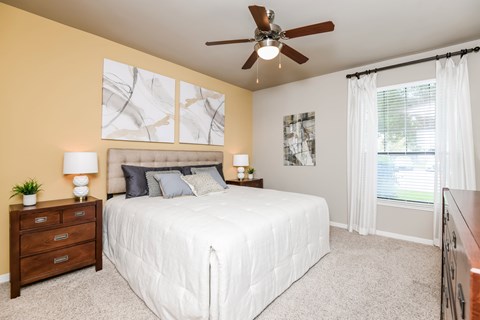 A bedroom with a bed, nightstand, and a ceiling fan.